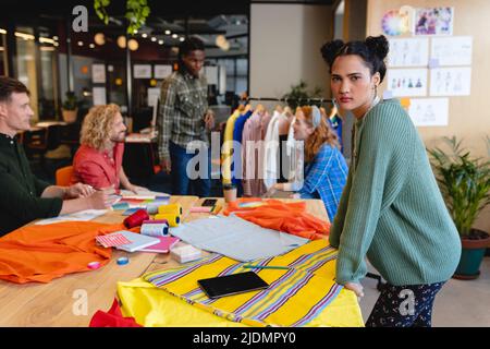 Portrait of confident caucasian female fashion designer with colleagues in office Stock Photo