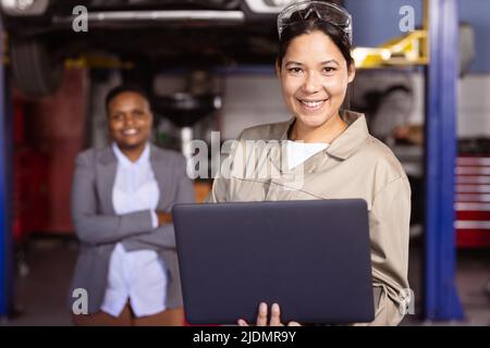 Portrait of confident smiling mid adult multiracial female mechanics working, copy space Stock Photo