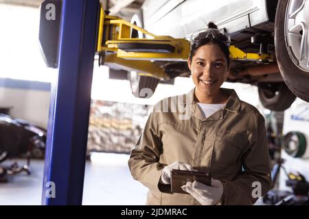 Portrait of smiling mid adult asian female engineer using digital tablet in workshop, copy space Stock Photo