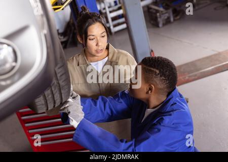 Multiracial mid adult female engineers working together while repairing car in workshop Stock Photo