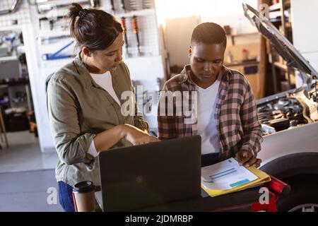 Mid adult multiracial female engineers discussing work while working in workshop Stock Photo