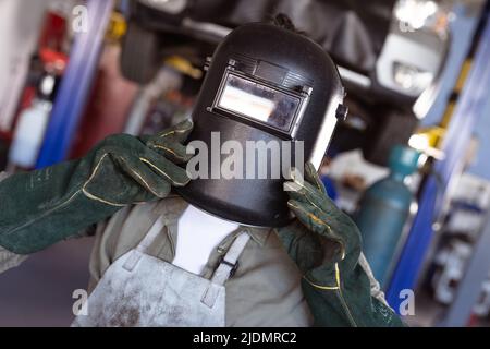 Mid adult asian female welder wearing protective mask and gloves while working in workshop Stock Photo