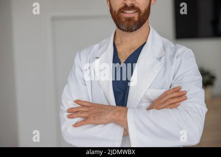 Close up of doctor in uniform with crossing hands standing in medicine clinic hall  Stock Photo