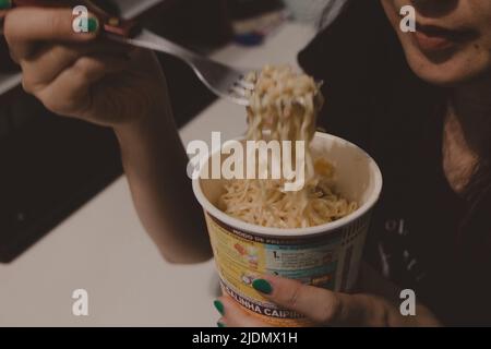 teen girl eating noodles in a cup Stock Photo