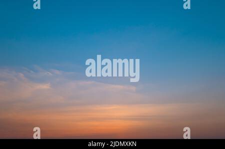 Bright orange sunset sky background with gentle colorful clouds, soft focus Stock Photo