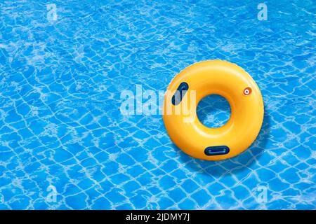 Yellow ring floating in a blue wave water on the outdoor swimming pool. Summer holidays Stock Photo