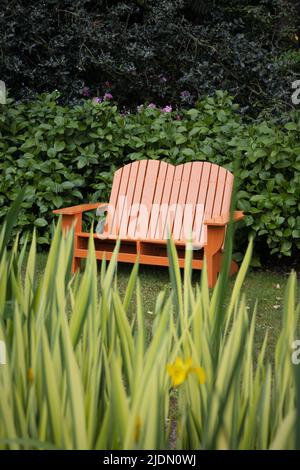 A pretty, colorful adirondack bench in a garden. Stock Photo