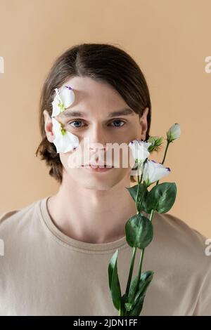 handsome boyfriend touching face of girlfriend with flowers on face  isolated on beige Stock Photo - Alamy