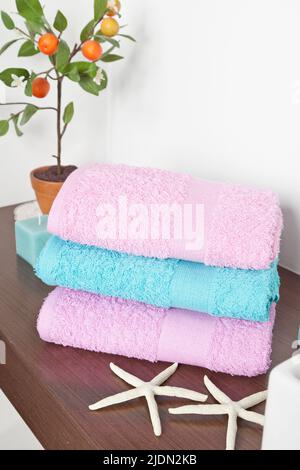 Bath towels of different colors in wicker basket on light background ...