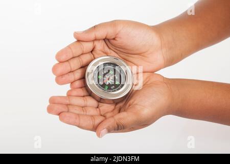 Child hands holding a compass on white background. Stock Photo