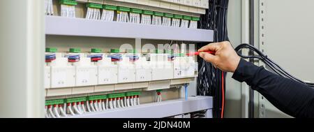 Electrical engineers check electrical control devices with a multimeter. Stock Photo
