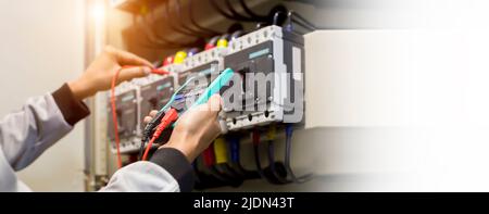 Electrical engineers check electrical control devices with a multimeter. Stock Photo