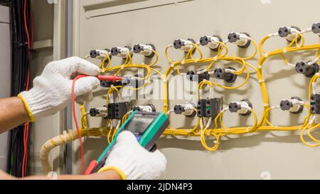 Electrical engineers check electrical control devices with a multimeter. Stock Photo