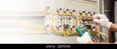 Electrical engineers check electrical control devices with a multimeter. Stock Photo