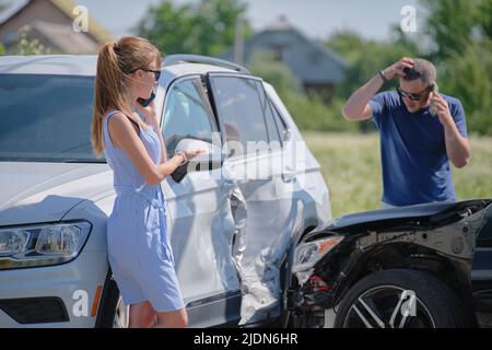 Drivers of smashed vehicles talking on cellphone calling for help in car crash accident on street side. Road safety and insurance concept Stock Photo