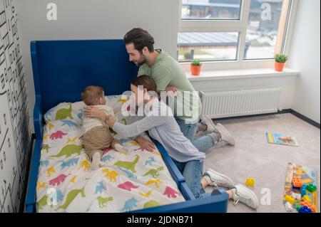 Parents putting a baby to bed and looking happy Stock Photo