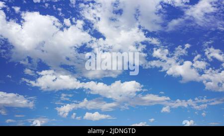 Puffy clouds against a sunny blue sky. Stock Photo