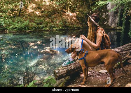 Woman Hiking in Mountain Forest with Dog Stock Photo