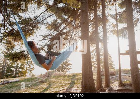 Male sleeping and resting hammock in forest. Beautiful nature. Relaxing in wood. Wild tourism. Stock Photo