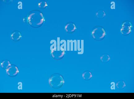 pure clean iridescent soap bubbles floating in the air with a beautiful clear blue sky background. Stock Photo