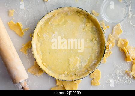 Tart Pan Filled with Raw Pastry Dough: Uncooked pie crust in a tart pan shown with a rolling pin Stock Photo