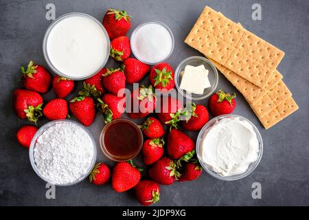 Strawberry Cheesecake Mousse Ingredients on a Dark Background: Fresh strawberries, cream cheese, graham crackers, and other dessert ingredients Stock Photo