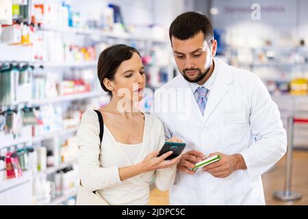 Male pharmacist consulting woman customer in drugstore Stock Photo