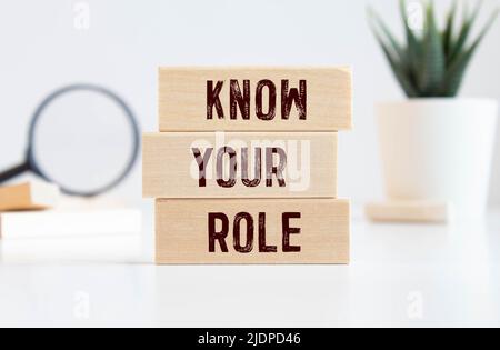 Business message KNOW YOUR ROLE written with chalk on wooden mini blackboard labels, defocused chalkboard and wood table in background Stock Photo