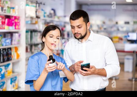 Female pharmacist consulting male customer in drugstore Stock Photo