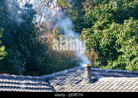 Smoke rises from a chimney on a house Stock Photo