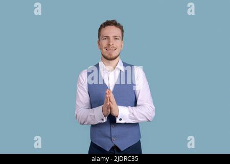 Good job, business man gesturing with his hands smiling broadly, giving positive feedback, sharing his positive opinion in a white shirt and blue vest on a blue background Stock Photo