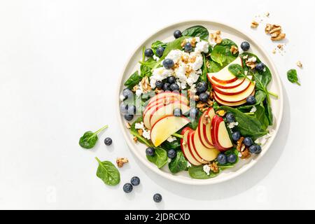 Apple and spinach fresh sweet fruit salad with blueberry, cheese cottage and walnuts, top view Stock Photo