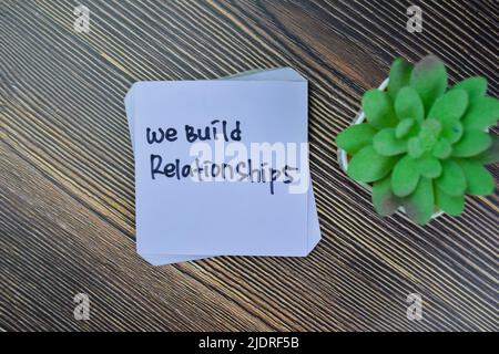 Concept of We Build Relationships write on sticky notes isolated on Wooden Table. Stock Photo