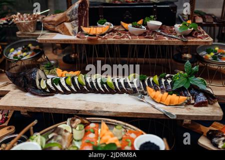 Serving and food exhibition of assorted pices of fish and smoked meat with beautiful decor on tray. Portion of tasty cold appetizer, nutritious dish Stock Photo