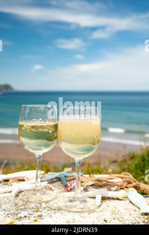 Tasting of txakoli or chacolí slightly sparkling very dry white wine produced in Spanish Basque Country, served outdoor with view on Bay of Biscay, At Stock Photo