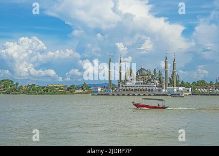 A motorised boat cruising in Sungai Terengganu River with Crystal Mosque or Masjid Kristal in the background in Kuala Terengganu, Malaysia. Stock Photo