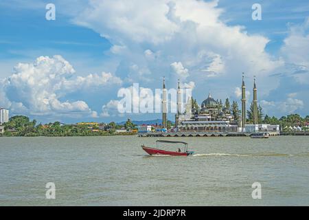 A motorised boat cruising in Sungai Terengganu River with Crystal Mosque or Masjid Kristal in the background in Kuala Terengganu, Malaysia. Stock Photo