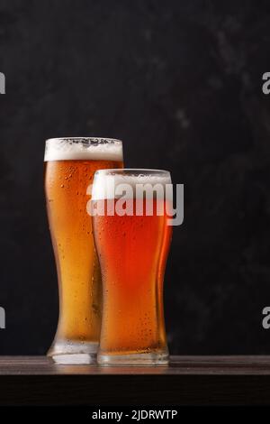 Two glasses of beer on black background. Alcoholic beverage over pub background. Stock Photo