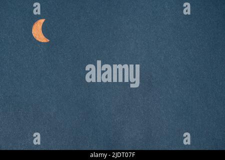 Orange metal crescent moon on navy blue kraft paper. Textured background with geometric shapes Stock Photo