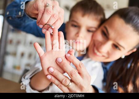 Mother carefully cuts her son's fingernails with nail scissors Stock Photo