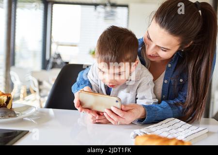 Mother and son video chatting together on smartphone at home in the living room Stock Photo