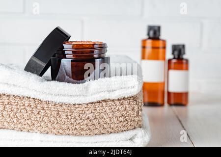 Spa composition with sea salt in glass jar, stack of bath towels, on a white wooden table, aromatherapy and skincare concept. Stock Photo