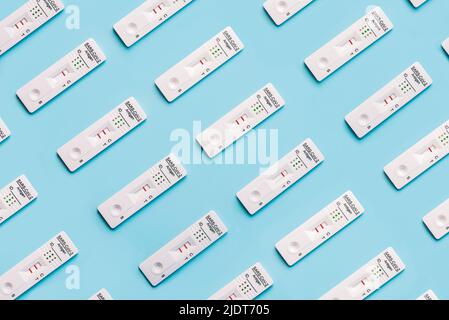 Top view of creative pattern made of rapid antigen test kits with different positive and negative for COVID-19 on blue background Stock Photo