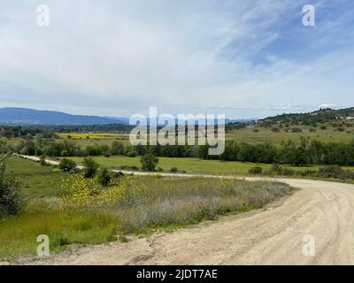 Winding dirt road through meadows and fields in the countryside of Southern Oregon, Pacific Northwest, United States. Stock Photo