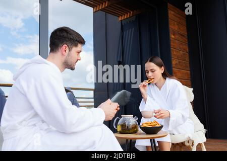 Cute couple in bathrobes having tea on the terrace Stock Photo