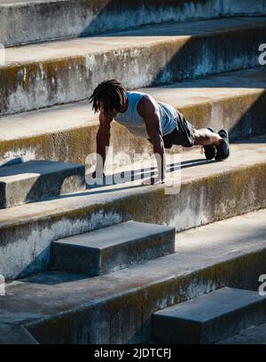 Athletic man doing push-ups on steps Stock Photo