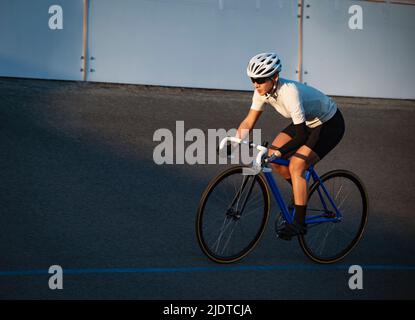 Athletic woman with prosthetic arm riding bicycle Stock Photo