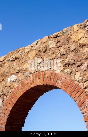 Antique, old monument ruin arch architecture made with rocks and bricks with blue sky in the background in europe Stock Photo
