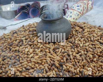 Heap of roasting raw peanuts, Smoke coming out of pot with peanuts below. peanut also known as the groundnut, goober, pindar or monkey nut. Stock Photo