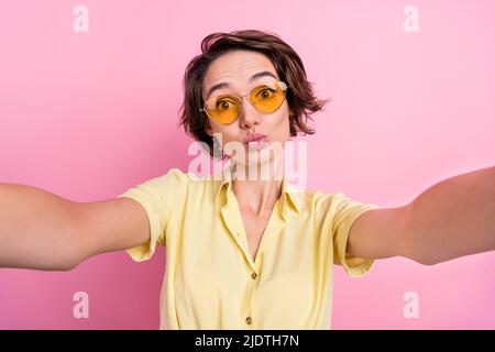 Photo of cute young brunette lady do selfie wear yellow t-shirt eyewear isolated on pink color background Stock Photo
